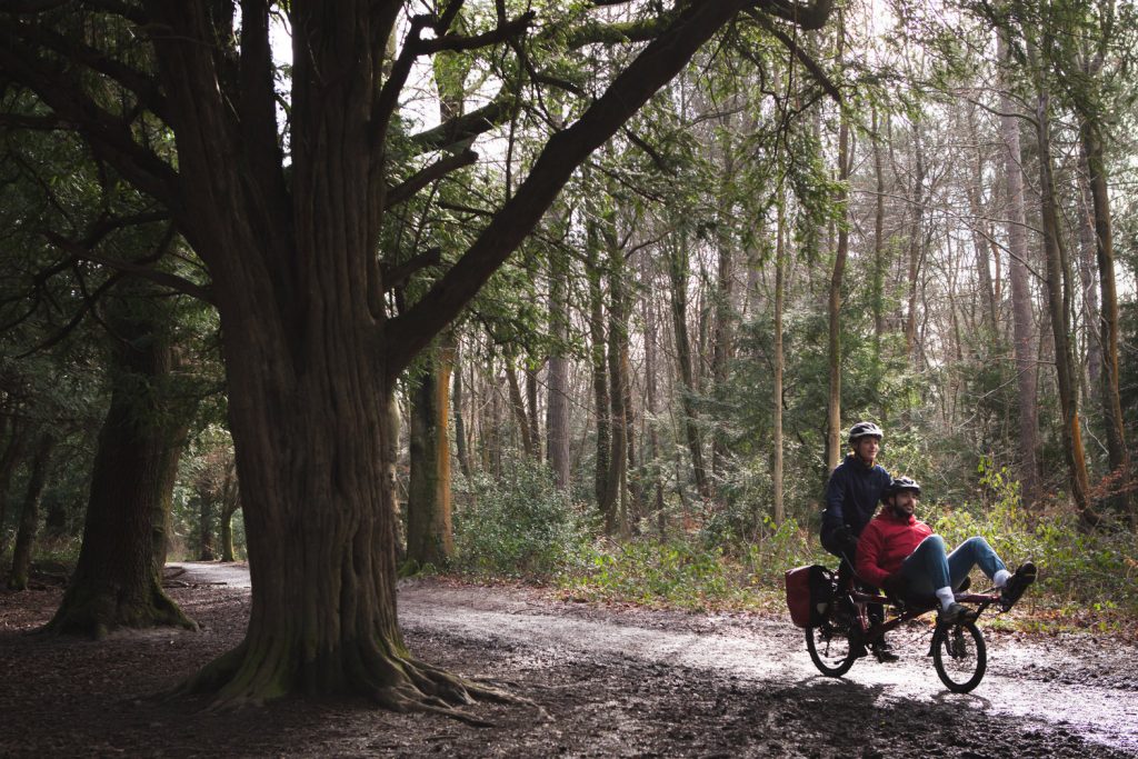 two ride tandem on a bike in the woods